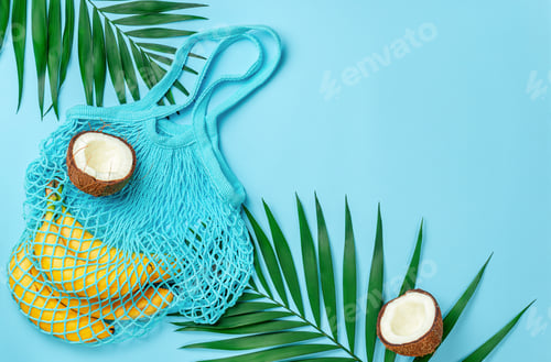 Preview: Zero waste mesh bag with bananas and coconut on bright blue background. Top view, copy space.