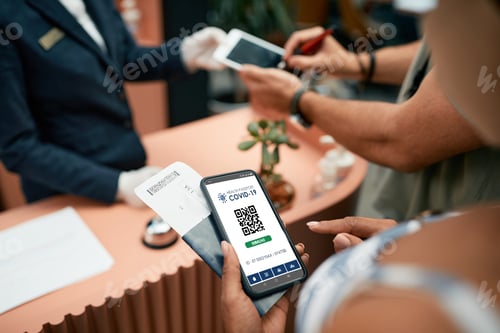 Preview: Close-up of woman using digital certificate of coronavirus vaccination during check-in a hotel.