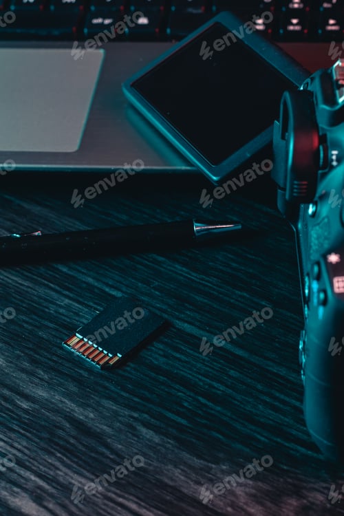 Preview: A workspace with laptop, modern camera, card and black pen on a wood desk