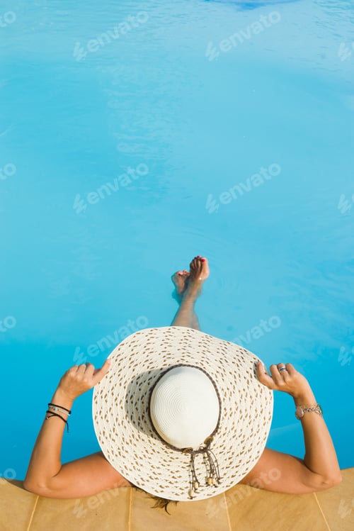 Preview: Woman in hat relaxing at the pool
