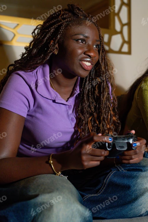 Preview: Young woman enjoying videogames with her girlfriend on the sofa