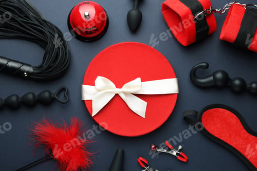 Preview: Flat lay composition with different sex toys and gift box on dark blue background
