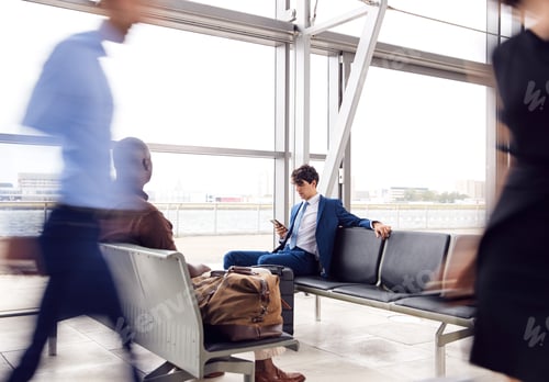 Preview: Business Passengers Sitting In Busy Airport Departure Lounge Using Mobile Phones