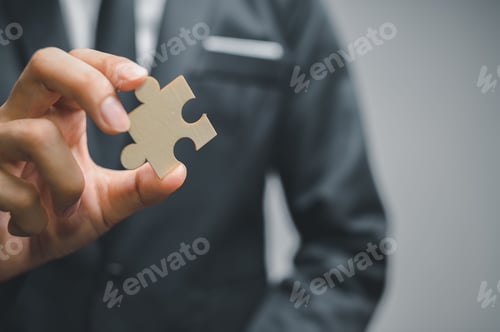 Preview: Concept of finding new solutions in a business, closeup of a man in a suit holding a jigsaw puzzle