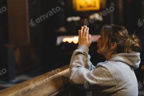 Preview: Woman praying on her knees in an ancient Catholic temple to God.
