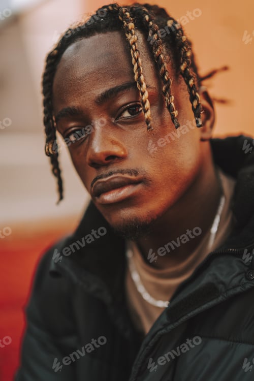 Preview: Handsome stylish Spanish man with dreads posing on a red blurred background