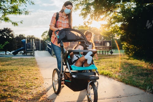Preview: Mother with mixed race children at take a stroll through a playground at sunset, mother wearing mask