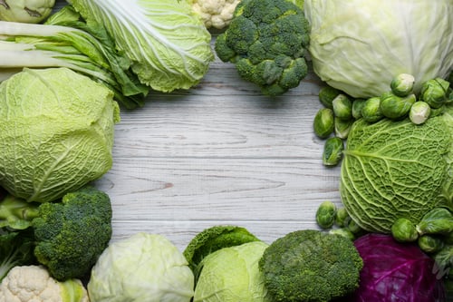 Preview: Frame of different cabbages on white wooden table, flat lay. Space for text