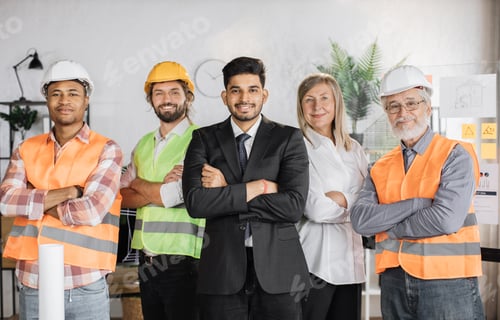Preview: Front view of builders, architects looking at camera while standing on light modern office.