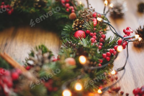 Preview: Christmas wreath decorations close up on rustic wood in lights.