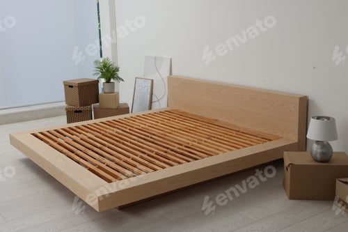 Preview: New wooden bed frame, moving boxes and decor elements indoors