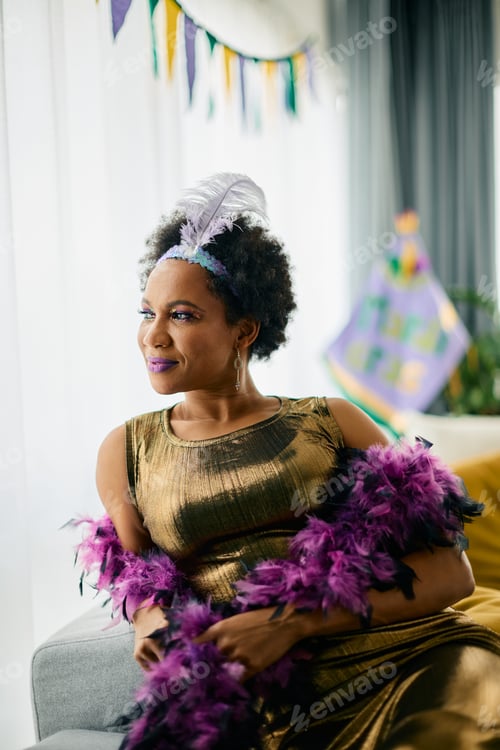 Preview: Beautiful black woman in Mardi Gras costume looking through the window at home.