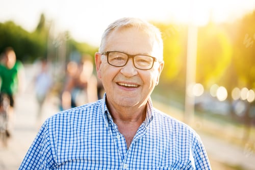 Preview: Smiling senior man with silver hair in park