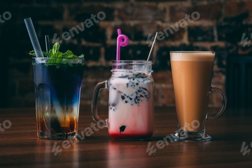 Preview: Closeup shot of a coffee, cocktail, and bubble tea in glasses with straws on a wooden table
