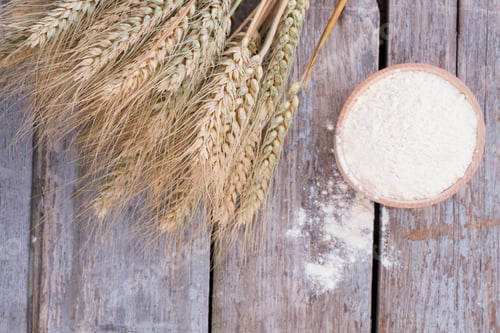 Preview: Wheat ears and bowl with flour on wooden background.
