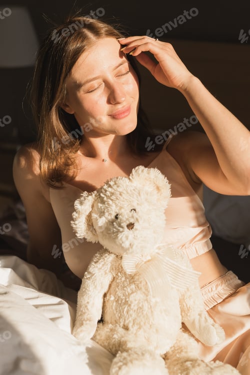 Preview: Portrait girl is waking up in morning stretches in bed and sun shines from the window. Happy young