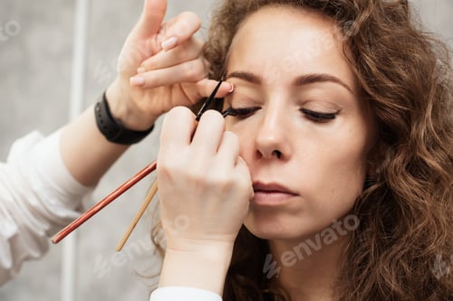 Preview: Shooting in a beauty salon. A young beautiful girl model master makeup artist puts shadows on the