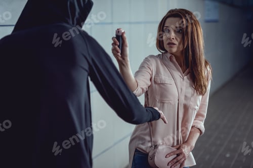 Preview: frightened woman pointing pepper spray at thief in underpass