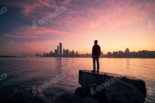 Preview: Man looking on cityscape at colorful dawn
