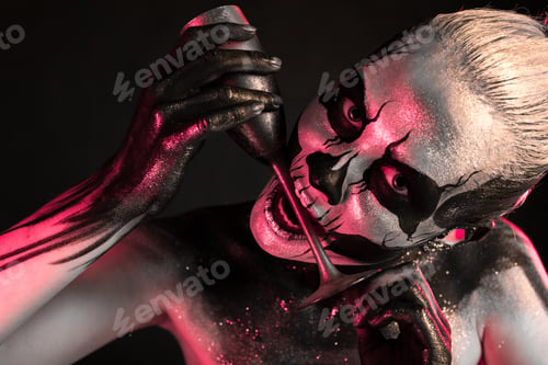 Preview: Pretty girl with skeleton makeup holds glass