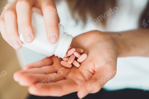 Preview: Close up woman hands holding vitamin pills, shaking them out of the bottle on the palm of her hand
