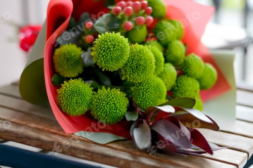 Preview: Bouquet of beautiful flowers wrapped in paper on wooden table, closeup