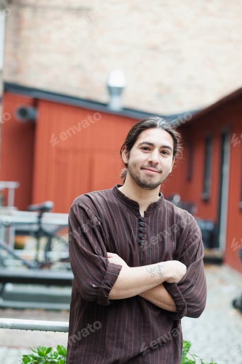 Preview: Portrait of confident man standing arms crossed at cafe backyard