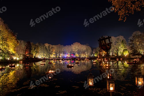 Preview: Aerial shot of a lake surrounded by street lamps and trees at night