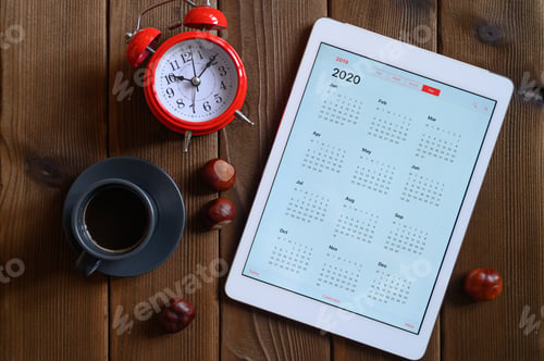 Preview: a tablet with an open calendar for 2020, a Cup of coffee, chestnuts and a red alarm clock