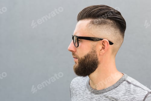 Preview: Side view of young bearded man isolated on gray background