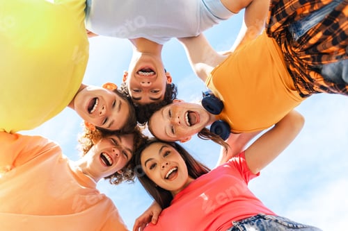 Preview: Several smiling teenagers smiling and looking down at camera, hugging