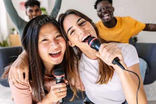 Preview: Multiracial young women having fun with friends playing karaoke at home party