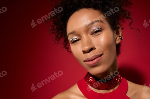 Preview: Portrait of a young woman radiating confidence against a vibrant red background