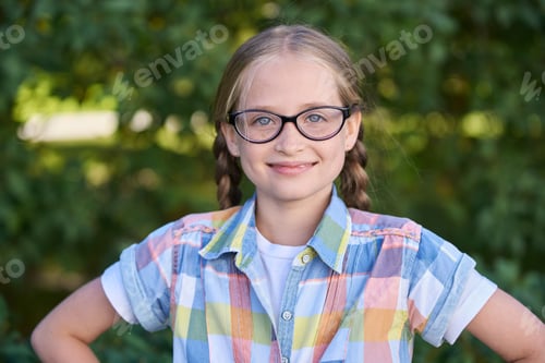 Preview: Smiling caucasian female child with glasses in plaid shirt outdoors in nature