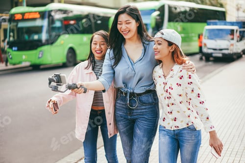 Preview: Happy asian girls streaming video with mobile phone at city bus station