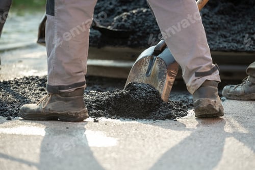 Preview: Closeup low angle view of worker arranging fresh asphalt mixture