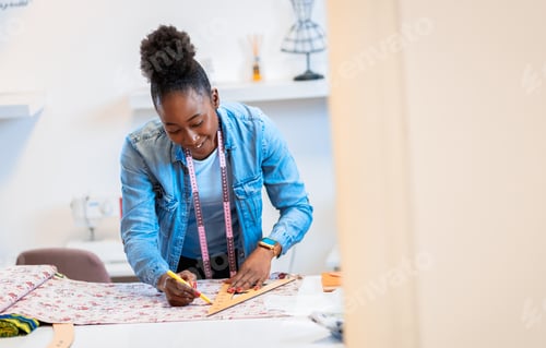 Preview: Female fashion tailor working on the measurements for the dress design in her workshop.