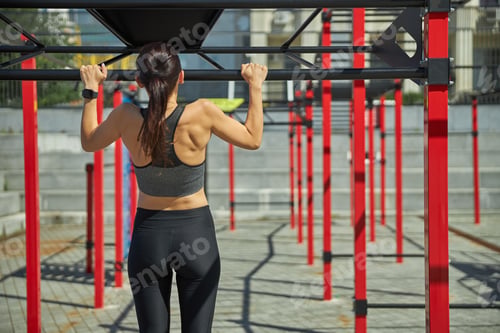 Preview: Strong young woman pulling up on the bar