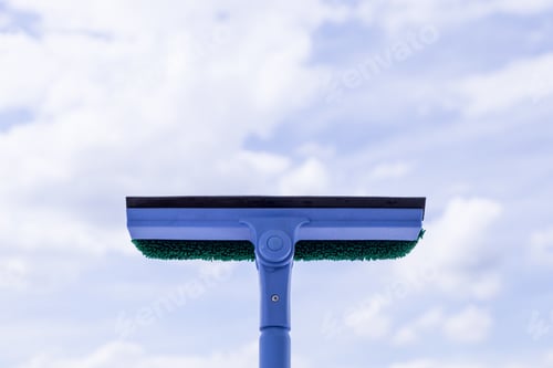 Preview: Cropped female hand washes window glass with a brush on the handle and detergent