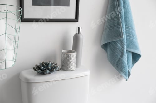 Preview: Decor elements, necessities and toilet bowl near white wall. Bathroom interior