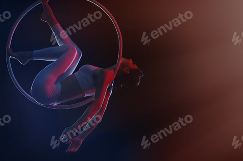 Vista previa: Mujer joven realizando un elemento acrobático en un anillo aéreo sobre fondo oscuro. Espacio para texto