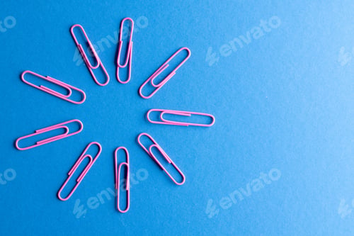 Preview: Close up of pink paper clips in circle and copy space on blue background