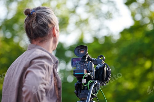 Preview: Rear view to man videographer recording outdoor movie about nature on professional camera, TV crew