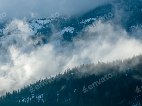 Preview: Misty Mountain Ridge Above Snowy Forest With Clouds Over Howe Sound, BC, Canada