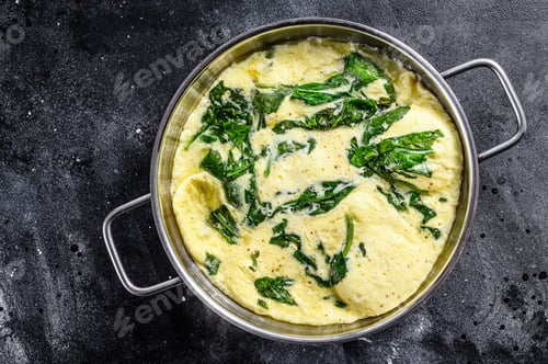 Preview: Italian Spinach and Cheese Omelet in a pan. Black background. Top view
