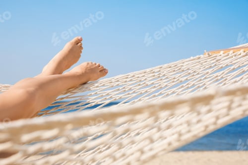 Preview: Young woman relaxing in hammock on beach, closeup