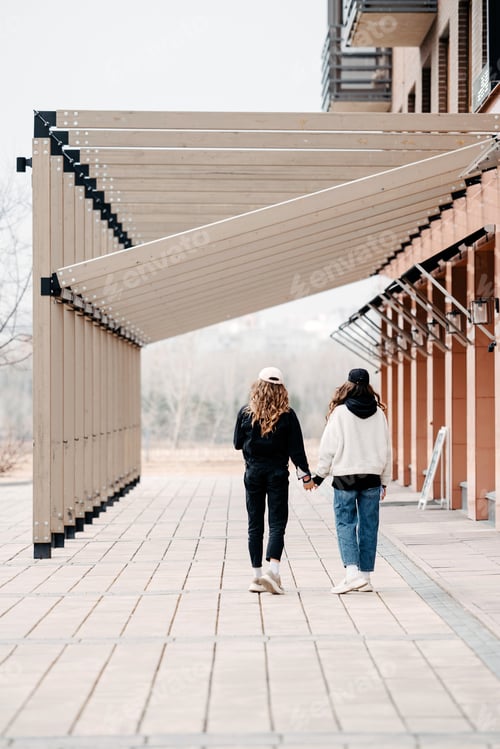 Preview: Two teenager girls hold hands. Youth culture and fashion