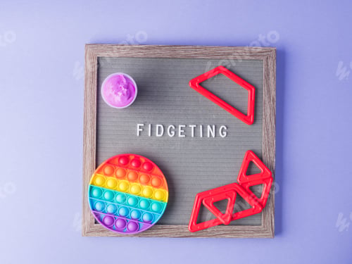 Preview: Colorful fidget toys to reduce stress and anxiety on purple with letter board saying Fidgeting