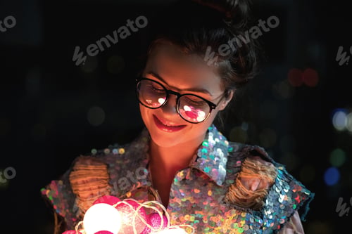 Preview: Happy woman wearing glowing jacket with sequins is holding light balls in her hands
