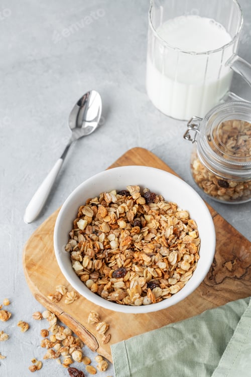 Preview: Homemade baked granola or muesli in a bowl on a wooden board on a light background